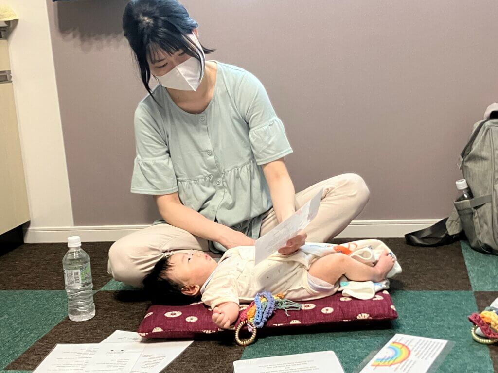 寝転がった赤ちゃんを前にする母親