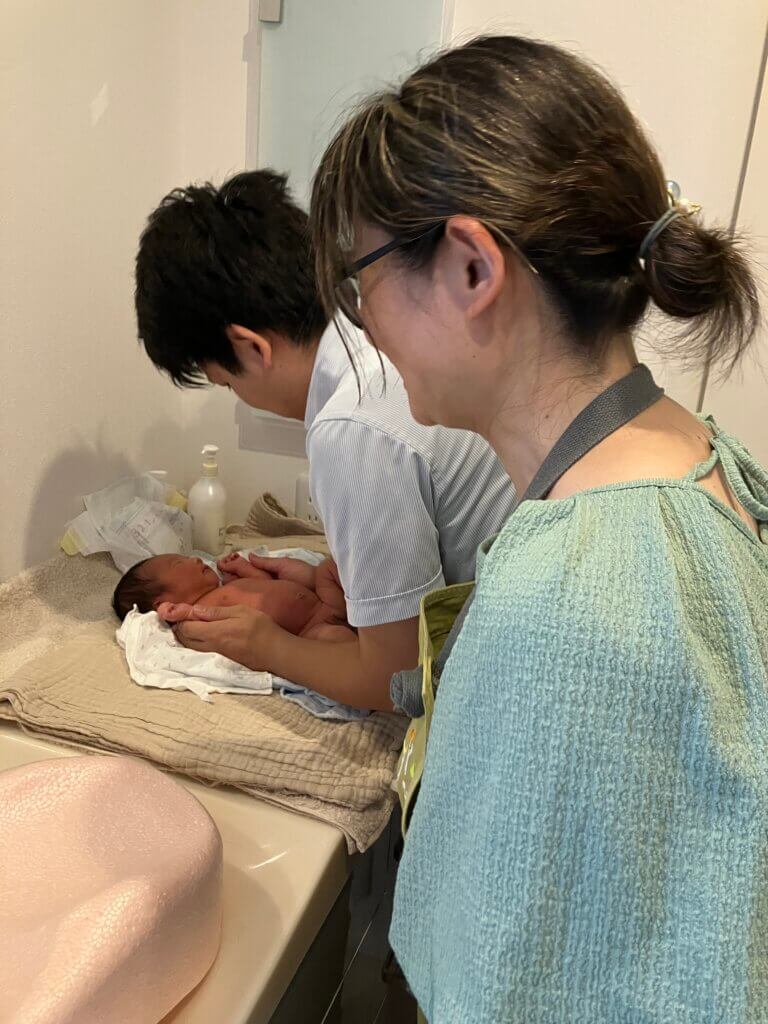 父親に沐浴指導中の助産師の写真